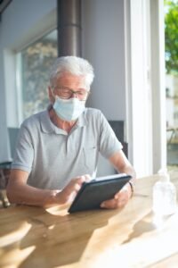 elderly man wearing face mask using a tablet
