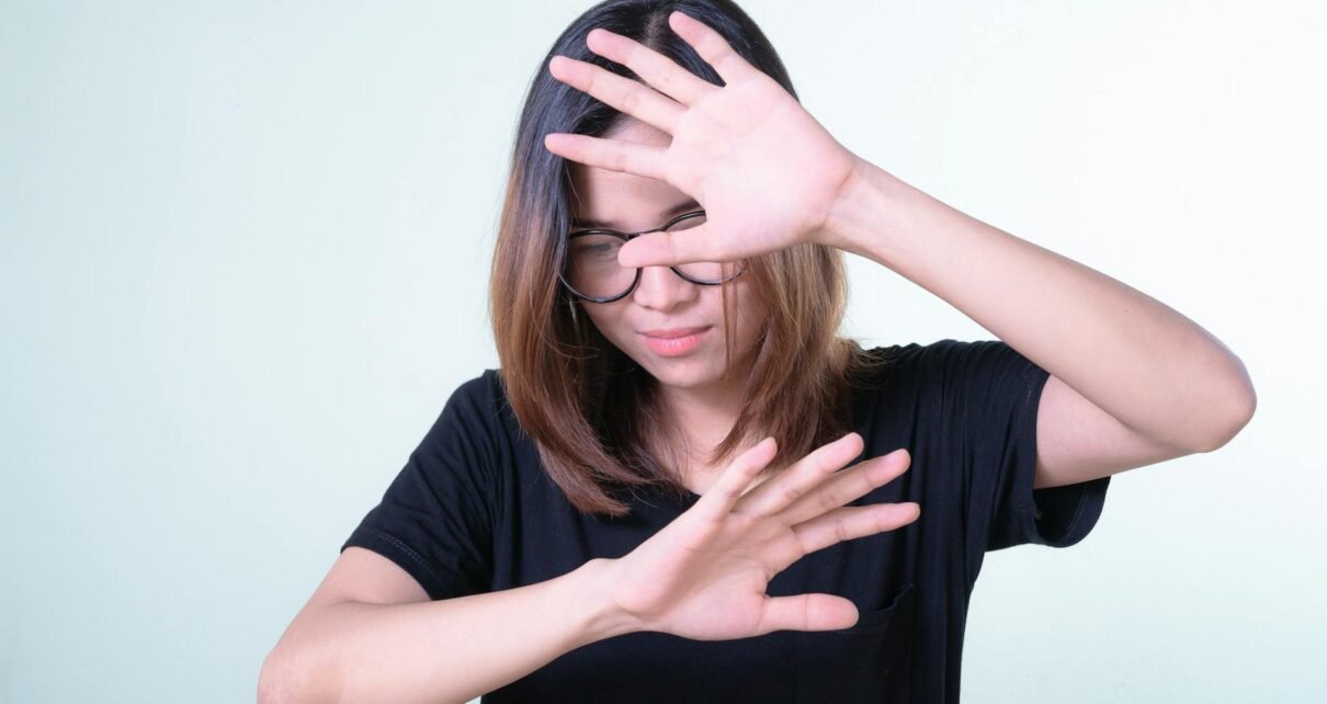 woman in black shirt covering face with her hands